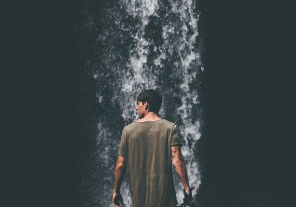 A man standing in front of a waterfall.