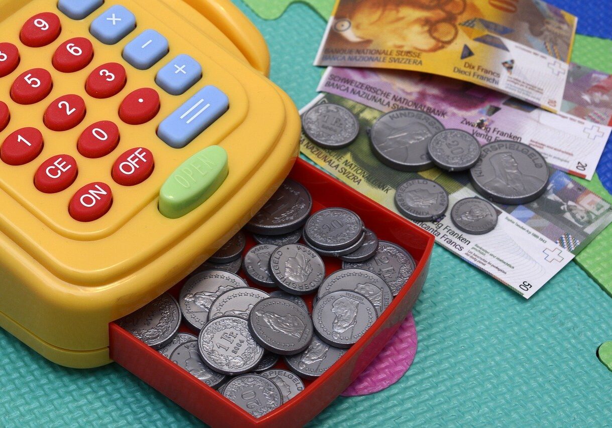 A toy cash register with coins and money in it.