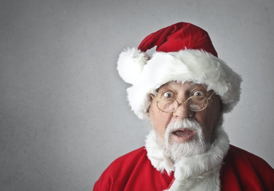 A man in santa clause costume with surprised look.